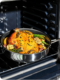 Roasted chicken with vegetables in a pan inside an oven.