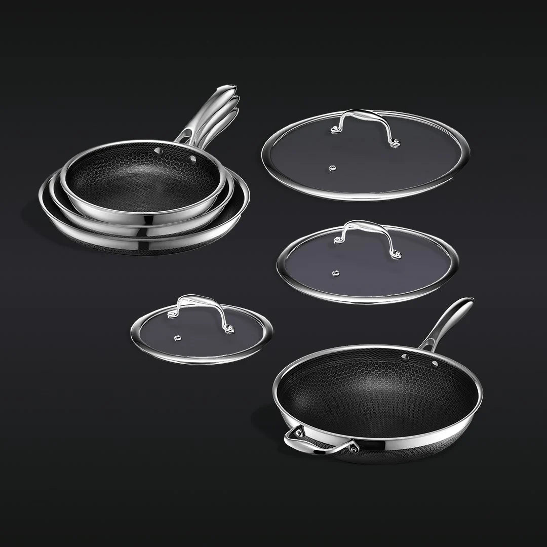 Stacked frying pans and lids on a dark background.